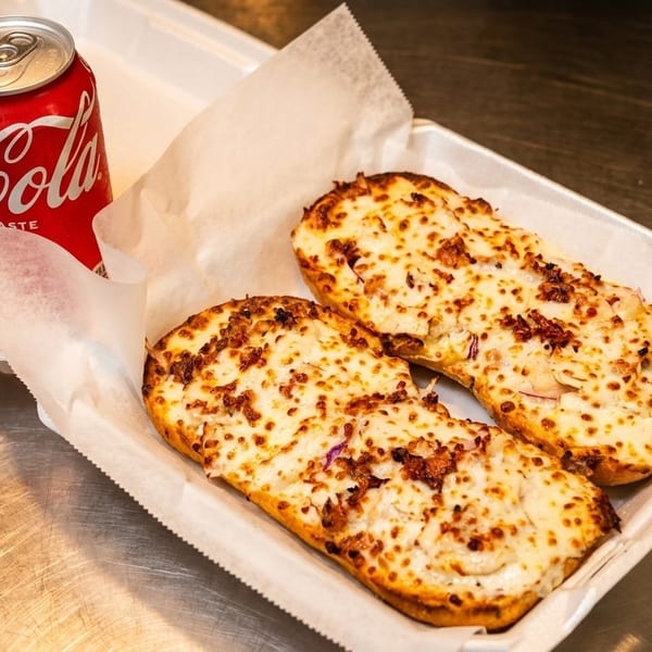 Two cheesy breadsticks with toppings and a red Coca-Cola can in a white takeout container.