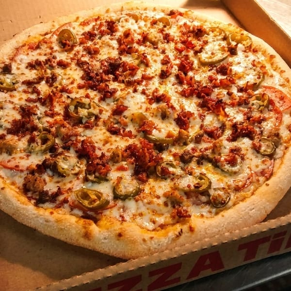 A whole pizza with cheese, pepperoni, jalapeños, and tomatoes in a Pizza Time box.